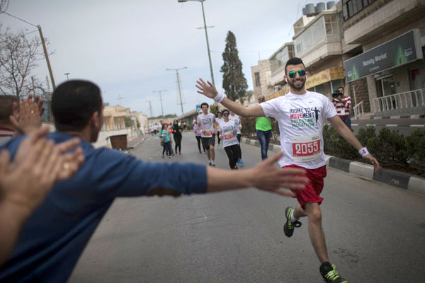 Runner receiving encouragement from a spectator in the Palestine Marathon, 2015, Bethlehem, Palestine (Occupied Territories). Photo courtesy Uriel Sinai for New York Times